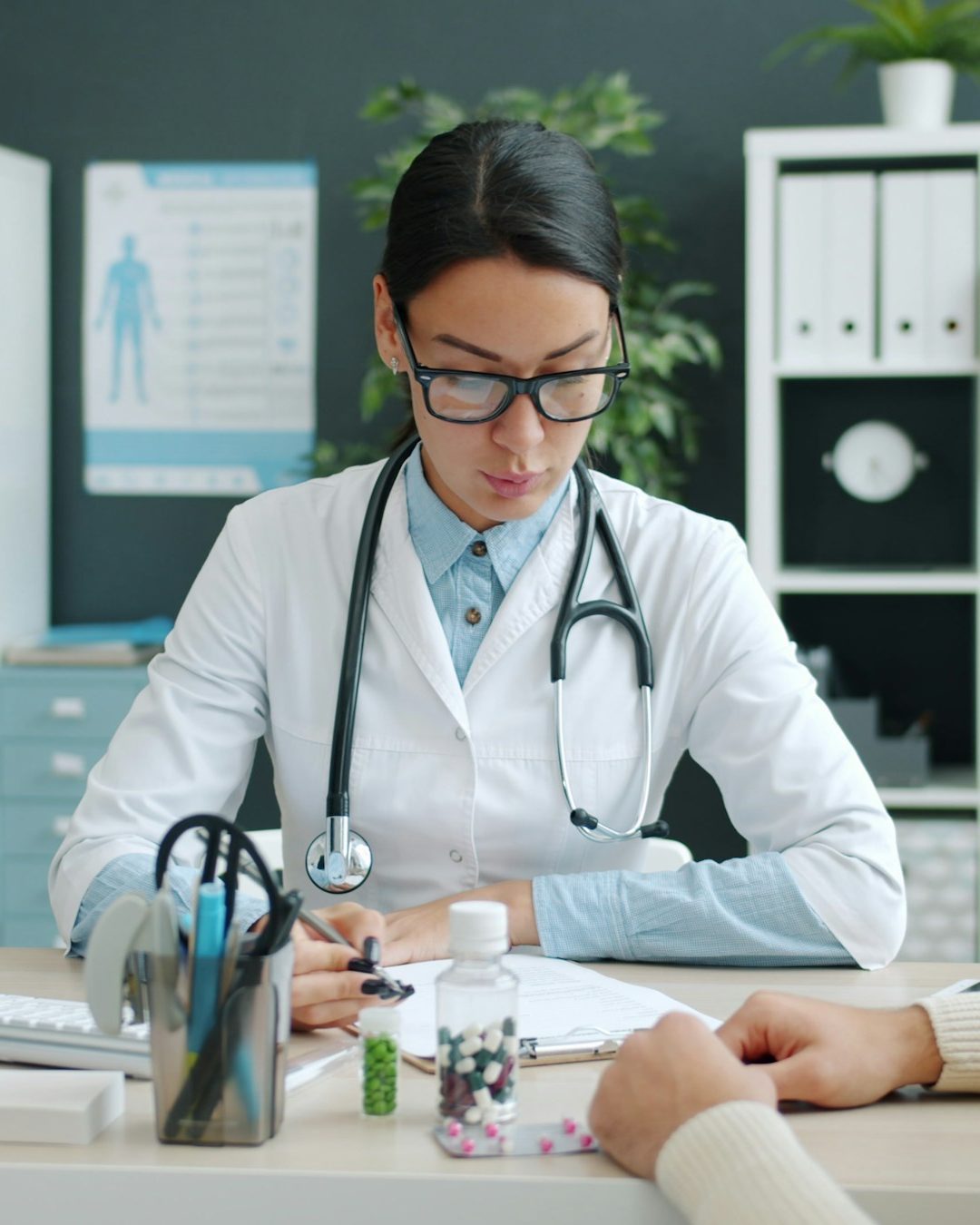 Moderne Website für eine Klinik, Beispielansicht: Ärztin mit Brille und Stethoskop im weißen Kittel sitzt am Schreibtisch und bespricht mit einem Patienten seinen Befund